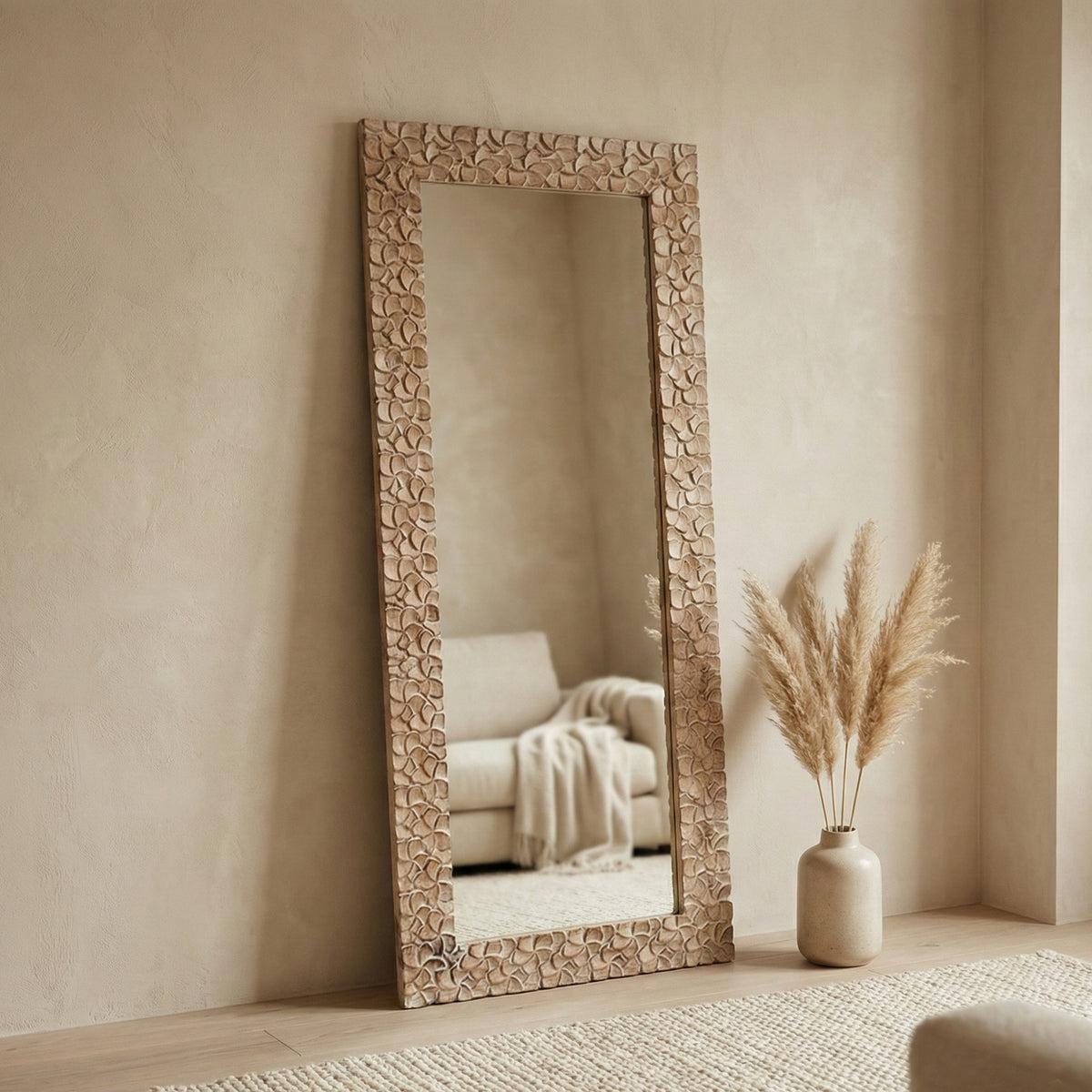 Decorative floor mirror with intricate carvings in a room with a couch and vase.