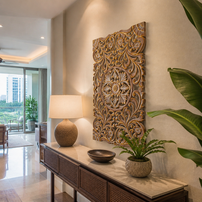 A large rectangular carved wooden wall art piece with intricate floral and scroll motifs in warm brown and gold tones, displayed on a beige wall above a console table in a modern interior setting.